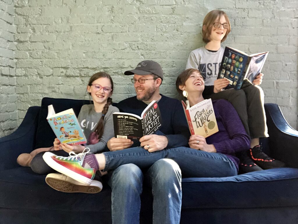 A family photo of Carissa with her family sitting on a couch, laughing and reading books.